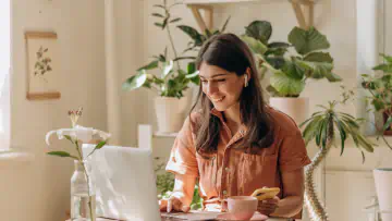 Woman at desk uses laptop