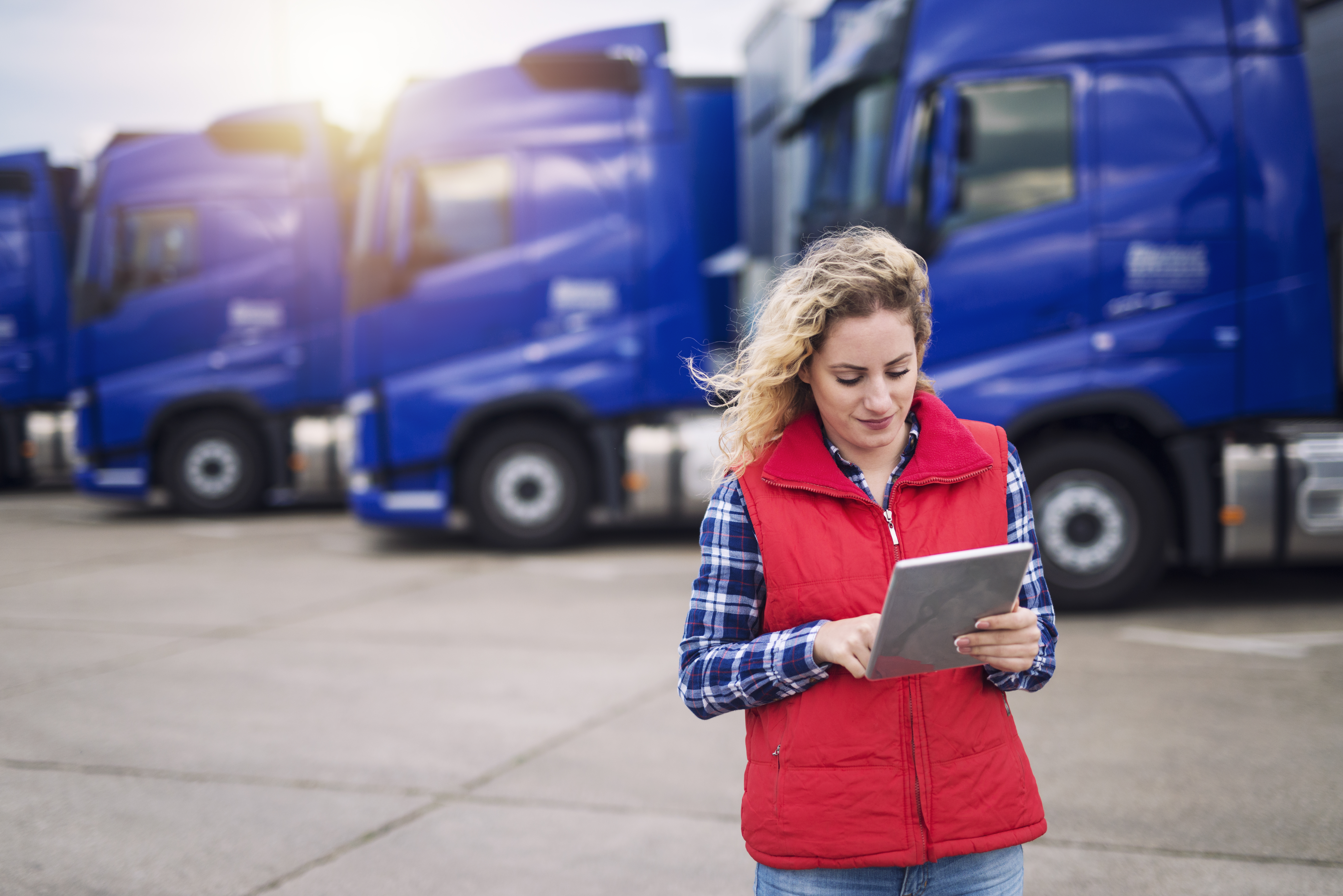 Female truck driver looking at a tablet.
